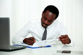 African man signing document in office