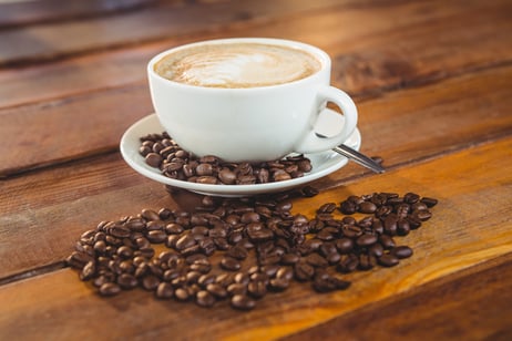 Cappuccino with coffee beans on table in cafeteria