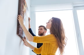 Happy couple hanging picture on the wall at home